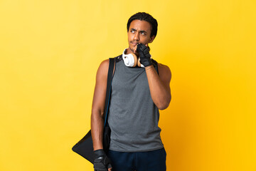 Young sport African American man with braids with bag isolated on yellow background and looking up