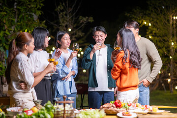 A group of people are gathered around a table with food and drinks