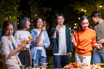 A group of people are standing around a table with wine glasses and food