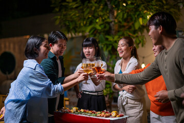 A group of people are gathered around a grill, drinking beer