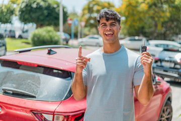 Young hispanic with car keys pointing up a great idea