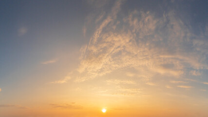 panorama view of a sunrise or sunset showcasing vibrant hues of yellow, orange and blue and fluffy cloud nature background
