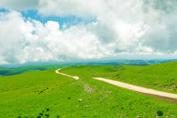 Beautiful view of a dirt road and alpine meadows in a mountainous area