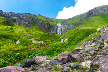 Picturesque landscape with beautiful Terskol waterfall, green slopes and steep cliffs. Caucasus, Elbrus region.