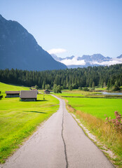 Schöne Berg Straße in Mittenwald Deutschland Alpen. Panorama Sicht auf Feld, Gebirge und Wiese.  See Idylle wandern durch Wald und Natur. 
Beautiful mountain road in Germany alps. Panorama view field
