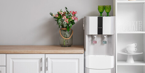 Interior of kitchen with modern water cooler near grey wall