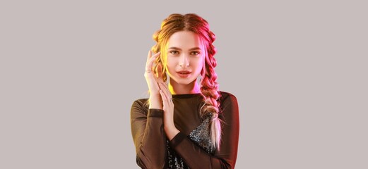 Beautiful young woman with braided hair on grey background