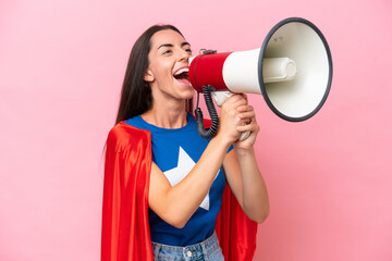 Super Hero Caucasian woman isolated on pink background shouting through a megaphone