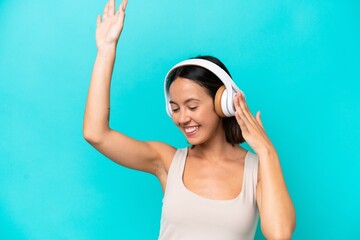 Young caucasian woman isolated on blue background listening music and dancing