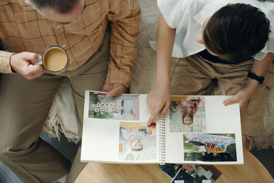 High angle view of grandfather telling about their family to his grandson while they watching family album at home