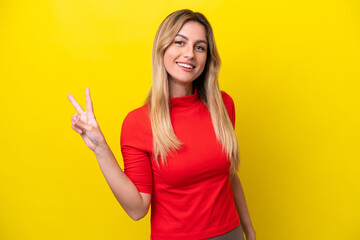 Fototapeta premium Young Uruguayan woman isolated on yellow background smiling and showing victory sign