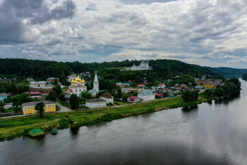 Fototapeta premium A stunning view features the Klyazma River flowing by Gorokhovets, surrounded by lush greenery and colorful homes.