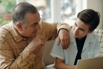 Fototapeta premium Grandfather talking to his grandchild while he using laptop