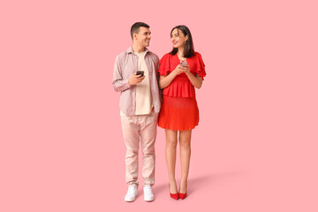 Young couple with mobile phones on pink background. Online dating