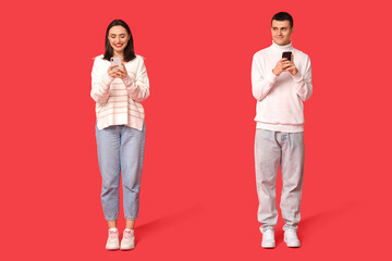 Naklejka premium Young couple with mobile phones on red background. Online dating