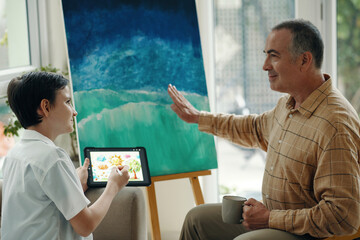 Grandfather discussing difference between modern art and computer art together with his grandson