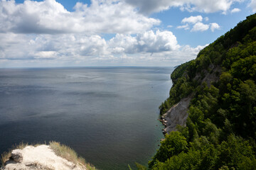 Breathtaking view of Vilga Rivers calm waters bordered by lush green cliffs under a dynamic sky filled with clouds.