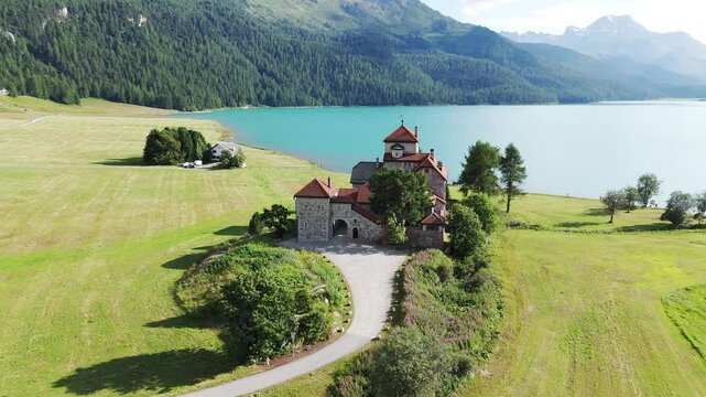 Orbit aerial view of historic castle overlooking Lake Silvaplana, St. Moritz, Grisons Canton, Maloja Region, Switzerland. 