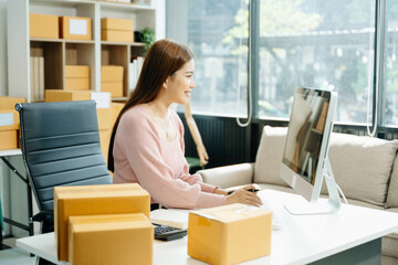 Naklejka premium Young businesswoman managing online sales and shipping from a modern home office.