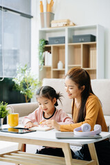 Cheerful mother and daughter sharing quality time on a couch, smiling and using a smartphone together.