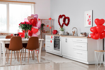 Interior of light kitchen with heart-shaped balloons and bouquet of roses on dining table. Valentine's Day celebration