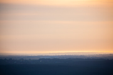 Golden and orange tones blend seamlessly in the sky as daylight fades, casting an enchanting glow on the land.
