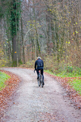 Fototapeta premium Male cyclist with winter sport clothing on racing bicycle passing at Zurich Airport on a foggy autumn day. Photo taken November 30th, 2024, Zurich Kloten, Switzerland.