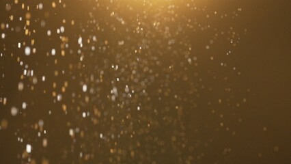Many sparkling golden glitters floating in warm light on empty background with light from above.