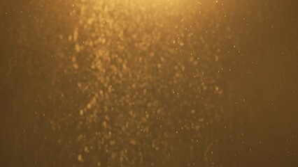 Many dust powder particles floating in warm light on empty golden background with spotlight from above.