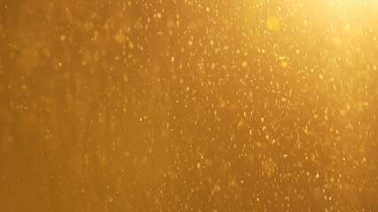 Many sparkling glitters floating in light on empty golden bright background with light from above.