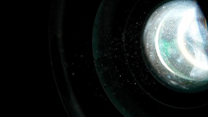 Many dust particles floating in front of flashlight on empty black background with spotlight from side.