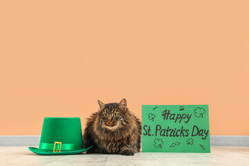 Cute cat with leprechaun hat and festive postcard for St. Patrick's Day celebration near beige wall