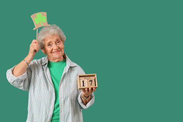 Happy senior woman with decorative leprechaun hat and calendar for St. Patrick's Day celebration on...