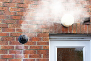 Condensing Gas Boiler Flue Steam Vapor Emitted from Black Pipe on Red Brick Wall with glass window...