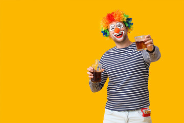 Young man as alcoholic clown with bottle of whiskey and cigarettes on yellow background
