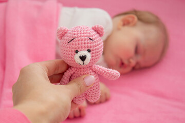 Baby sleeping on a pink background with a pink teddy bear.child