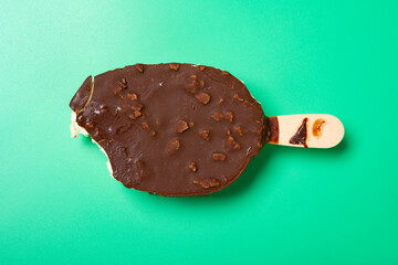 a chocolate outer popsicle with a bite on green background