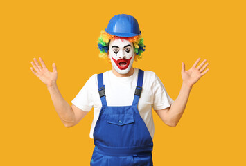 Surprised young man as clown in jumpsuit and helmet on yellow background