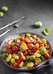 Brussels sprouts with chorizo ​​sausages, nuts and sesame seeds. Concept nutritious dish in a plate on a dark background