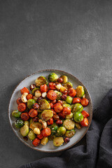 Brussels sprouts with chorizo ​​sausages, nuts and sesame seeds. Concept nutritious dish in a plate on a dark background