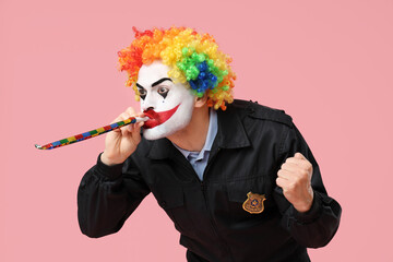 Funny young man as clown policeman with party whistle on pink background