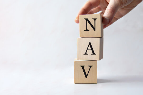 Female hand holding wooden cube with NAV letters on white background.