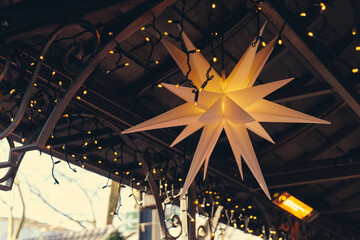Fototapeta premium Brightly lit star decoration illuminated under string lights in a cozy setting during evening hours