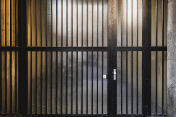 Black metal gates with vertical bars in a dimly lit urban environment during the evening