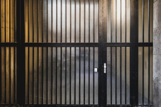 Black metal gates with vertical bars in a dimly lit urban environment during the evening
