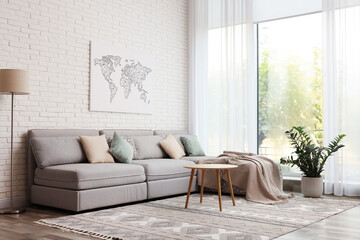 Stylish living room interior with comfortable sofa near white brick wall