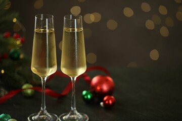 Delicious champagne in glasses and Christmas decor on grey table against blurred lights, space for text