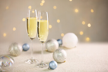 Delicious champagne in glasses and Christmas decor on white table against blurred lights, space for text