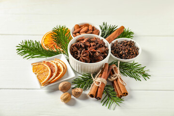 Different spices, dried orange slices and fir tree branches on white wooden table. Christmas season