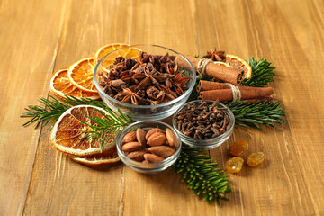 Different spices, dried orange slices and fir tree branches on wooden table. Christmas season
